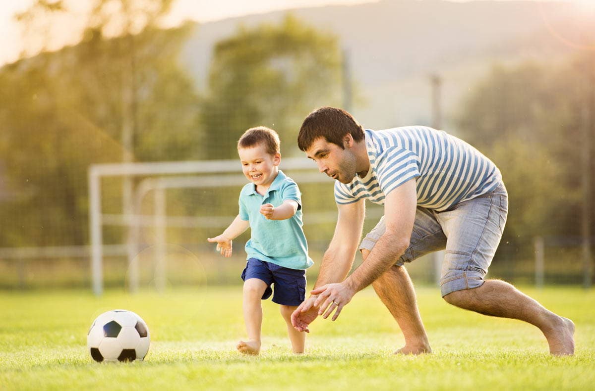 папа с сыном играют в футбол